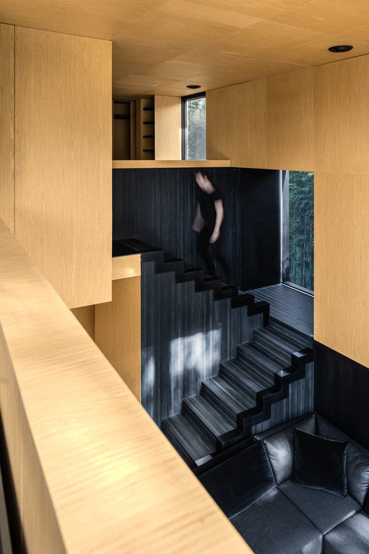 Escalera interior entre muros de madera clara