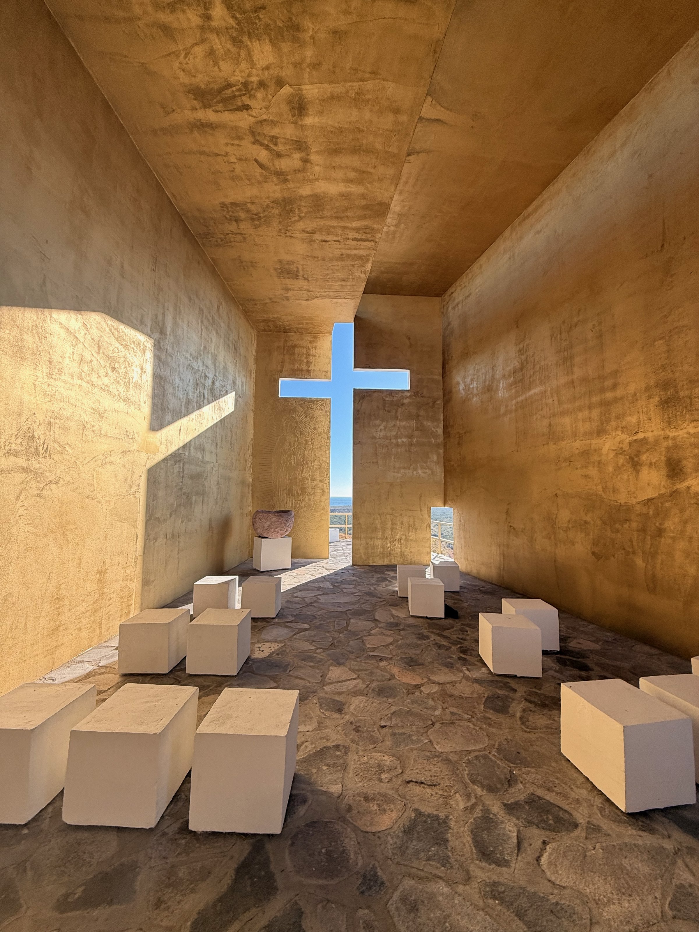 Interior con la cruz de luz azul y las bancas