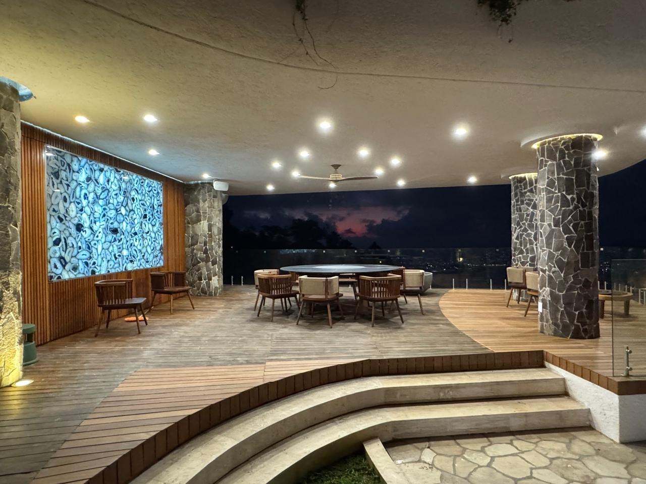 Comedor bajo la palapa, con el muro de piedra