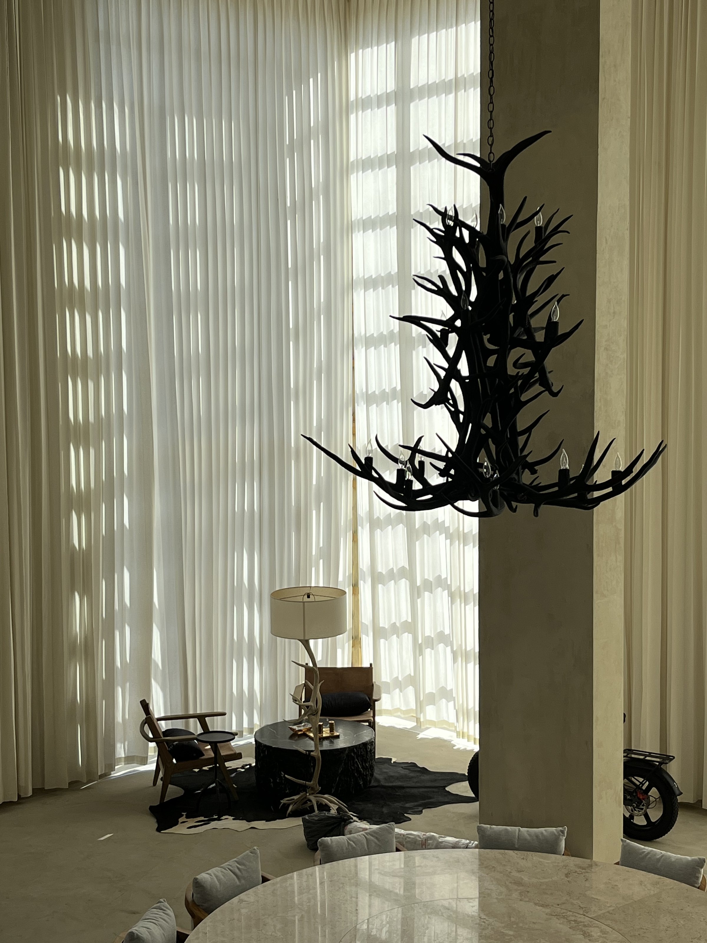 Comedor con candelabro de ramas frente a la cortina